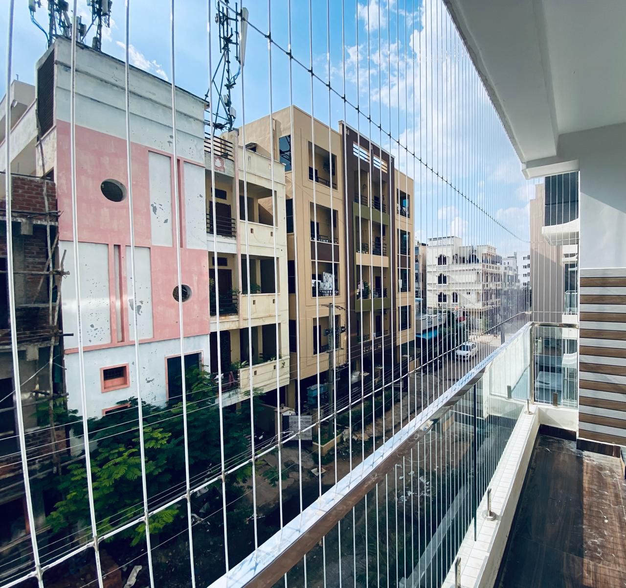Invisible grills installed on apartment building in Udupi Karnataka — clean satin finish SS316 cables on residential balcony coastal view