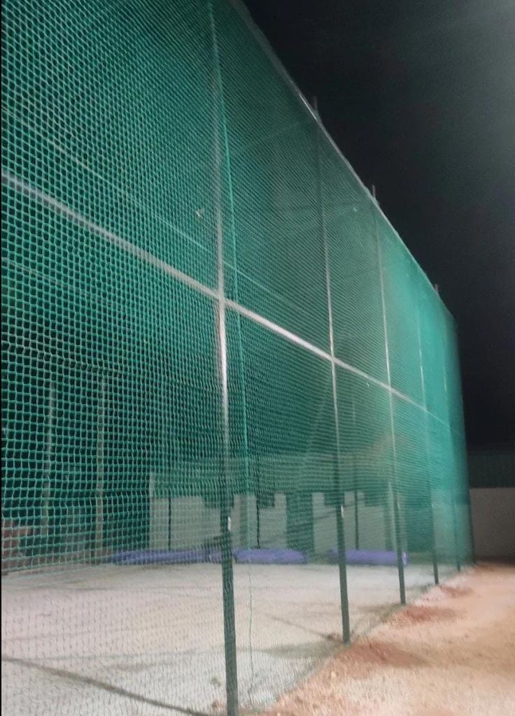 Ground level cricket net installation at residential plot in Andrapradesh — two cage setup with concrete footings GI frame and complete nylon net enclosure
